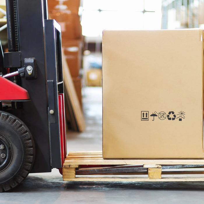 Forklift moving large cardboard box on pallet in warehouse, shipping and logistics