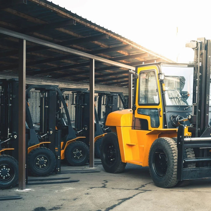 Multiple yellow forklifts parked under shelter in an industrial facility yard
