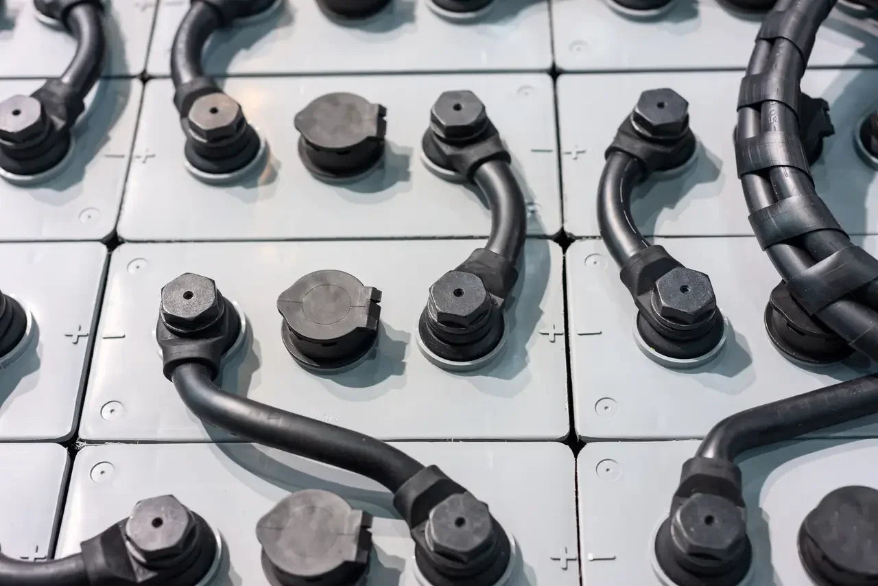 Close-up of industrial battery cells with black power cables connected.