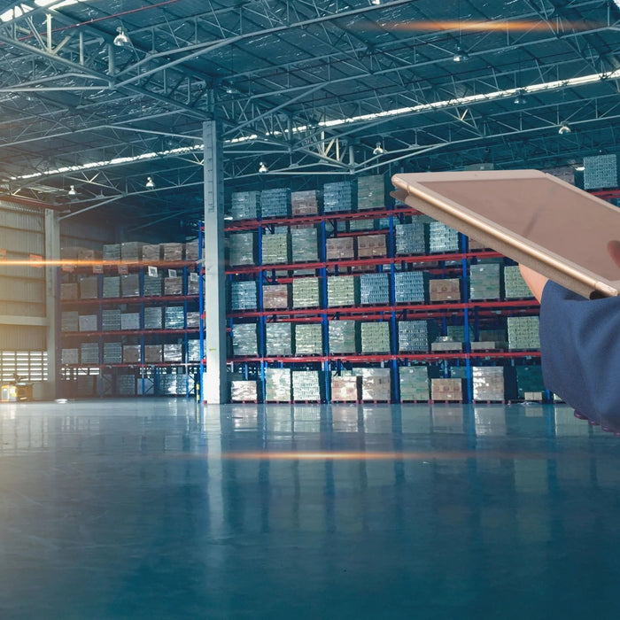 Person using tablet in modern warehouse with racks of stored facility power parts