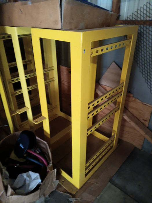 Yellow metal charger stand with open frame and slotted shelves in warehouse setting