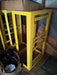 Yellow metal charger stand with open frame and slotted shelves in warehouse setting